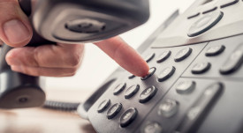 Closeup of male hand holding telephone receiver while dialing a